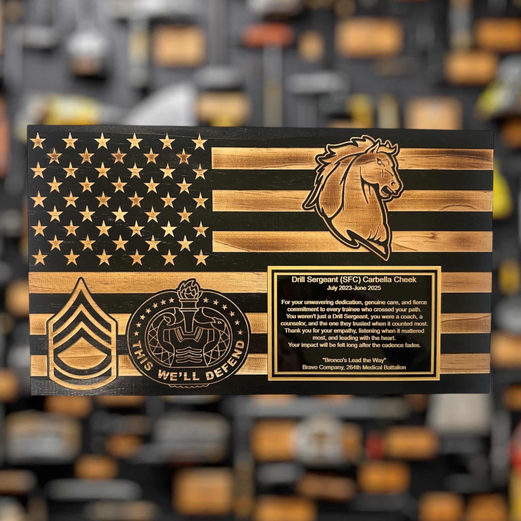 Wooden plaque military gift with American flag design, horse head emblem, army rank and engraved text on a blurred background.