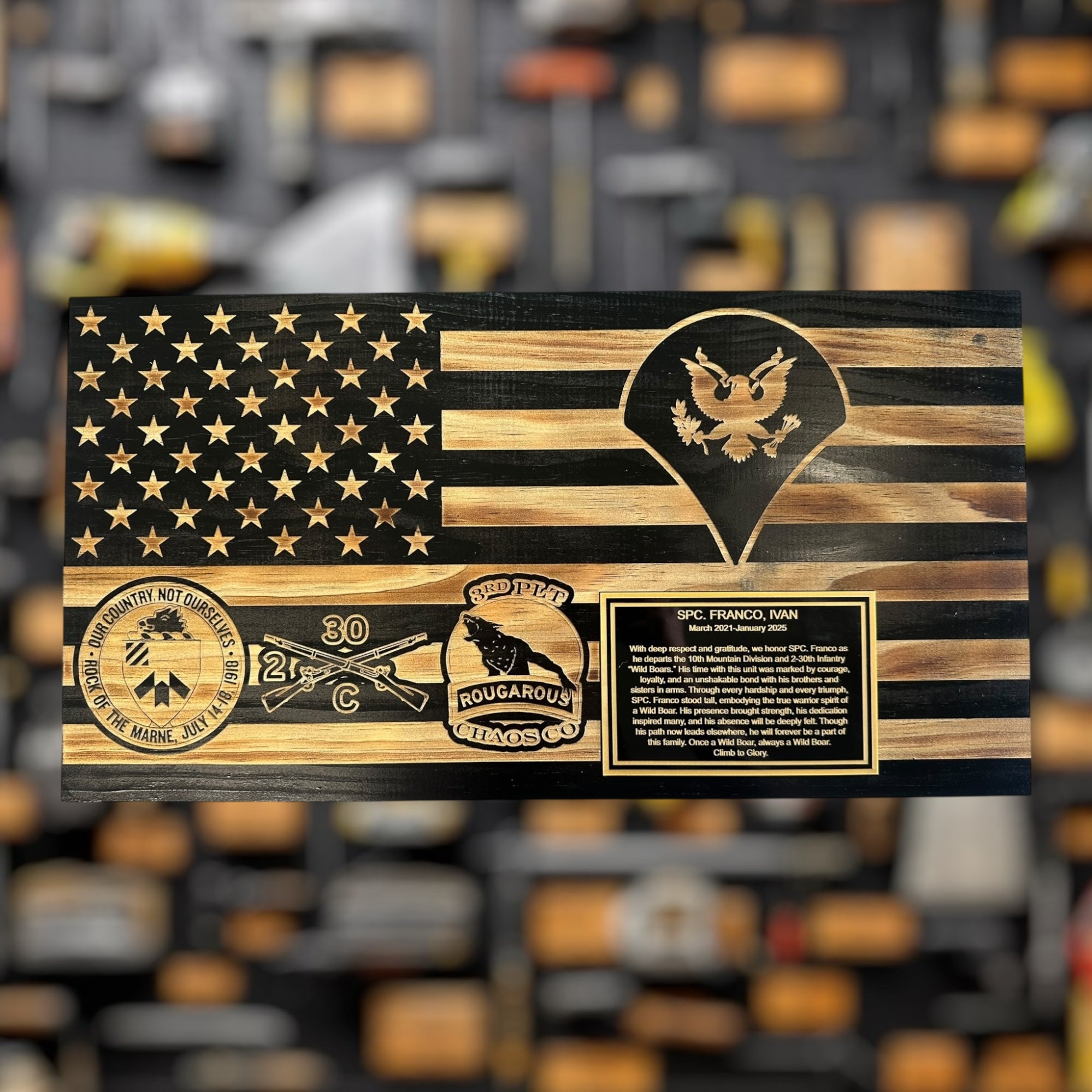 Wooden plaque military gift  with American flag design and military insignias and army unit logos on a blurred background